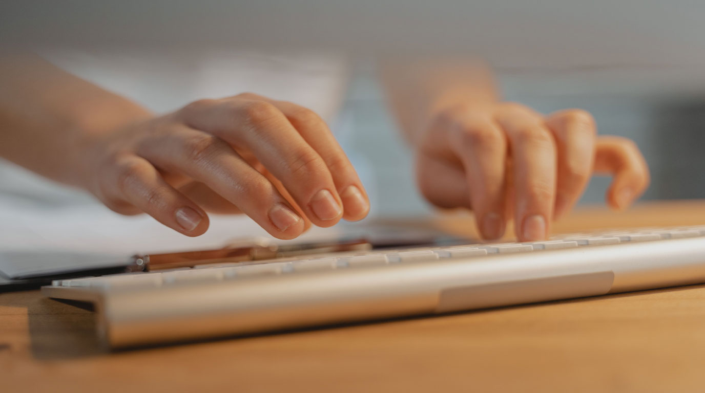 Hands entering patient data at a keyboard.